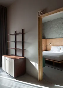 Modern minimalist bedroom featuring a wooden headboard and flooring, with a minimalist design and white bedding.