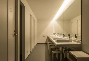 Modern white ceramic public toilets with sinks and mirrors.