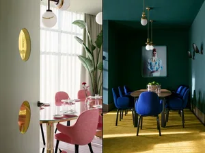 Modern restaurant dining room with round table, blue and pink chairs, round lamps, and yellow rug.