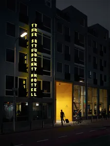 Nighttime view of the entrance to a student hotel, featuring illuminated signage and yellow lighting at the entrance.