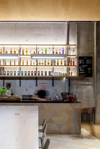 An industrial-style bar counter with a concrete finish, featuring shelves adorned with various bottles.