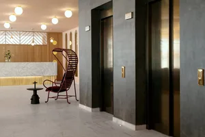 Modern hotel lobby featuring concrete, marble, metal, glass, and wooden finishes.