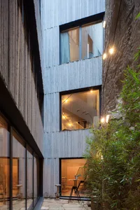 Modern residential exterior with metal siding, glass windows, and outdoor lighting.