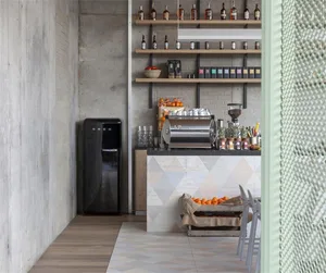 A modern industrial coffee shop with concrete shelving, featuring coffee-making equipment, oranges in a crate, and a SMEG ref