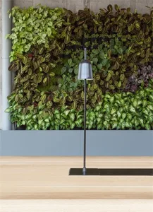 A modern vertical plant wall featuring various green plants and a sleek lamp.