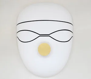 A white, metal mask with a yellow circular element