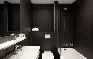 Minimalist bathroom featuring black tiles, a white countertop, and chrome fixtures.