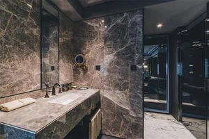 Modern bathroom with marble walls and countertop, featuring a vanity sink and towel rack.