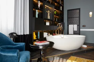 A modern bathroom featuring a freestanding tub with shelving unit, towels, and decorations.