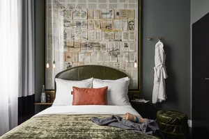 A well-designed modern bedroom featuring a concrete floor, a bed with a leather headboard, and a fabric bedspread.