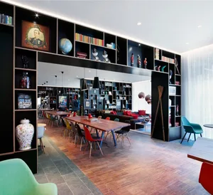 A modern coworking space featuring a combination of wooden furniture, metal accents, and glass elements, with a large bookshe