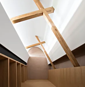 Interior of a modern building with wooden ceiling beams and light streaming through a large window.