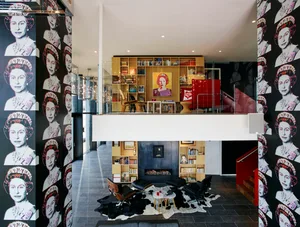 A modern living room with black and white portraits on the walls, wooden shelves, and a fireplace.