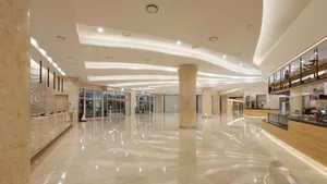 A spacious modern lobby with marble flooring and ceiling, featuring a counter on the right.