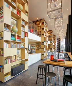 A modern restaurant bar featuring wooden furniture and shelves filled with books and globes.