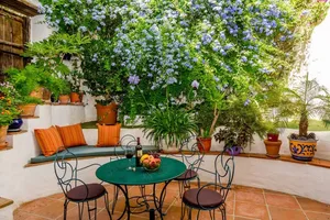 A cozy garden cafe with a green ceramic tiled floor, adorned with various potted plants and flowers, creating a serene and in