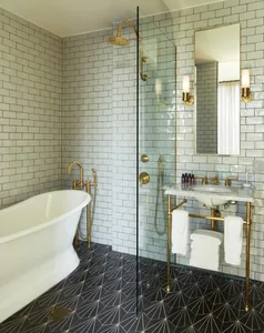 Modern, industrial-style bathroom featuring a freestanding bathtub, glass-enclosed shower, and black and white patterned floo