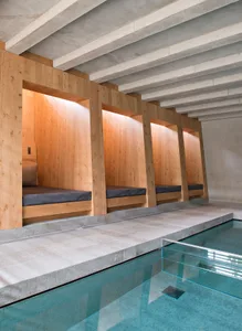 Indoor spa area with wooden platforms surrounded by a concrete wall.