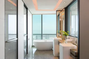 A modern bathroom featuring a white marble tub, sinks, and a glass enclosed shower.