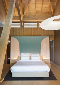 Modern minimalist bedroom with wooden furnishings and a large bed.
