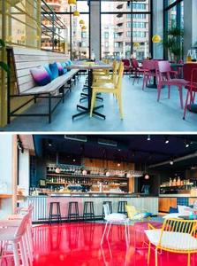 A modern cafe bar with metal painted flooring, fabric seat cushions on wooden furniture, plastic yellow chairs, glass tables,