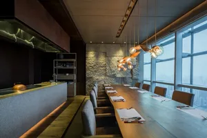 Modern conference room with wooden table, stone walls, and pendant lights.