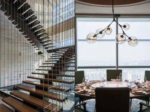 Modern dining room featuring metallic steel stairs and glass chandelier with hanging light bulbs.