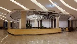 Modern hotel reception with marble circular ceiling panel and wooden counter.