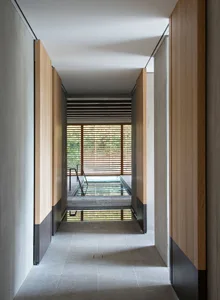 A minimalist interior hallway with wooden walls, concrete floors, and glass elements.