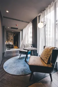 Modern interior living room featuring a cozy arrangement of a leather armchair, a round wooden table, and a patterned rug.