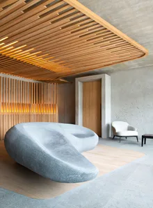 Modern living room with marble sofa, concrete wall, and wooden accents