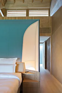 Modern minimalist bedroom featuring wooden furnishings and a fabric headboard.