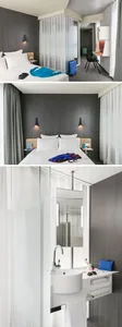 Modern minimalist hotel bedroom suite with textured dark grey walls, white bedding, and a sink with a towel rack.
