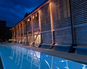 A modern residential building with a wooden exterior and a swimming pool on the side.
