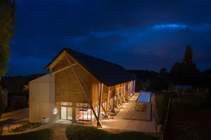 Modern resort building illuminated at night, featuring wood and concrete materials with night lighting.