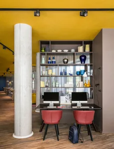 A modern workspace featuring a concrete shelf with a bookshelf and computer workstations.