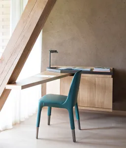 A minimalist modern workstation with a wooden finish, featuring a desk, a green chair, and a lamp.
