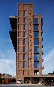 The exterior of The Williamsburg Hotel featuring a brick facade and large lettering spelling out the hotel's name.