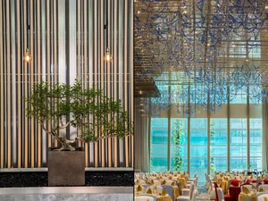 Modern event hall with metallic lighting, glass windows, and plants