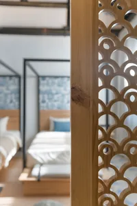 A modern bedroom featuring a carved wood screen with intricate designs.