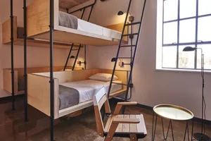 A modern bedroom featuring wooden bunk beds with a ladder, a wooden chair, and a round table.