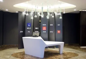 A minimalist hotel reception area with a sleek white desk, black walls, and modern light fixtures.