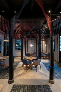 A modern industrial-style coffee shop interior with black metallic columns, concrete floor, and black and red artistic decora