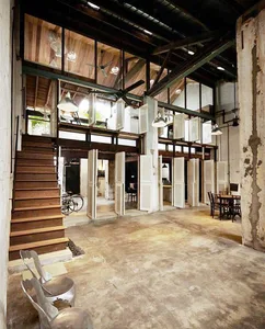 An industrial-style loft with concrete flooring, metal chairs, and open white window shutters.