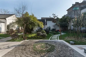 A serene garden featuring natural stones, grass, and trees.