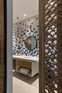 Modern minimalist bathroom with circular mirror, floating vanity, and blue and white scallop tile pattern on the wall