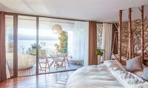 White minimalist bedroom featuring wood flooring, stone wall, and canvas lighting fixture.
