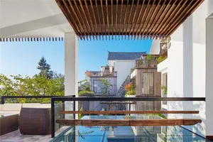 Modern-style balcony featuring white stone tiles and wooden elements under a clear blue sky.