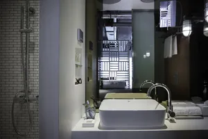 Modern bathroom with concrete walls and minimalist white vanity, featuring a white rectangular vessel sink with chrome fixtur