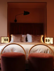 Modern bedroom with velvet upholstered headboard, plush pillows, and wall-mounted lamps.